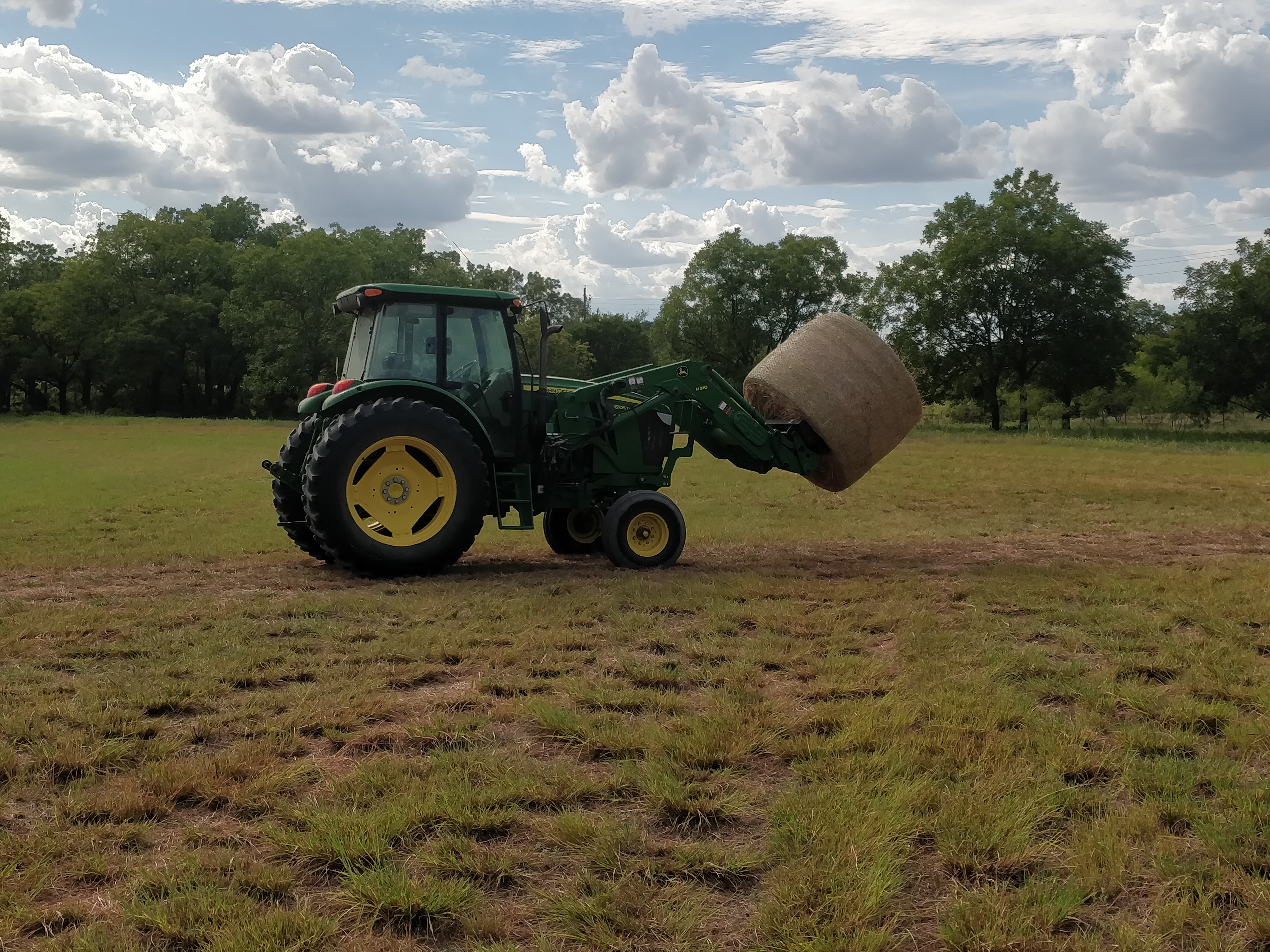 tractor moving hay bale on hay fork